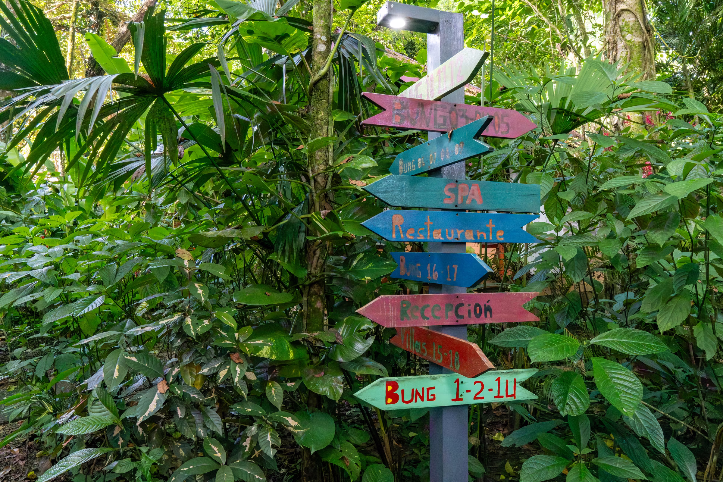 Hand-painted wooden signs pointing to the spa, restaurant, reception and bungalows