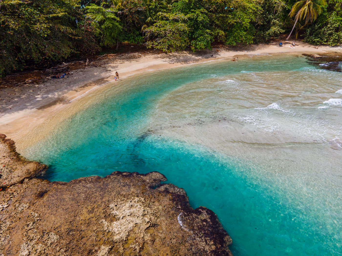 Aerial view of a turquoise Caribbean cove framed by rainforest near Namuwoki Lodge