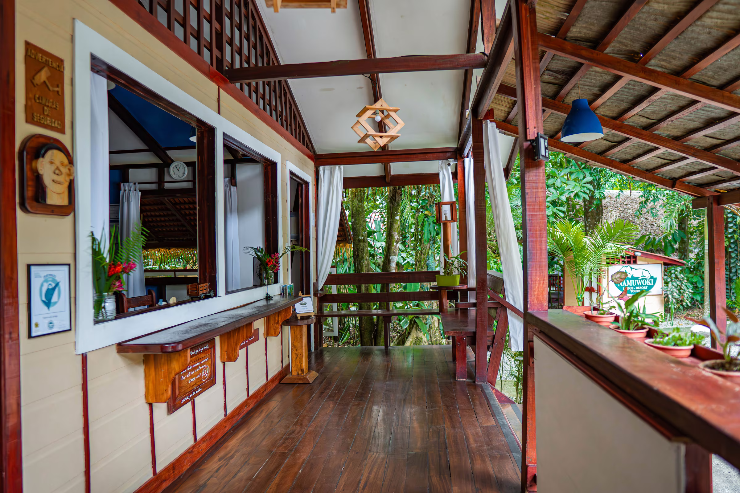 Wooden reception desk open to the surrounding jungle at Namuwoki Lodge